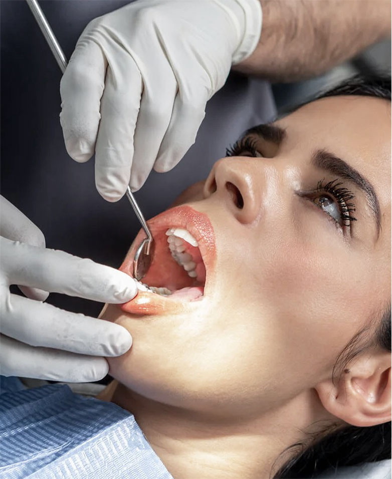 Dentist examining teeth of a female patient in dental clinic using dental tools.